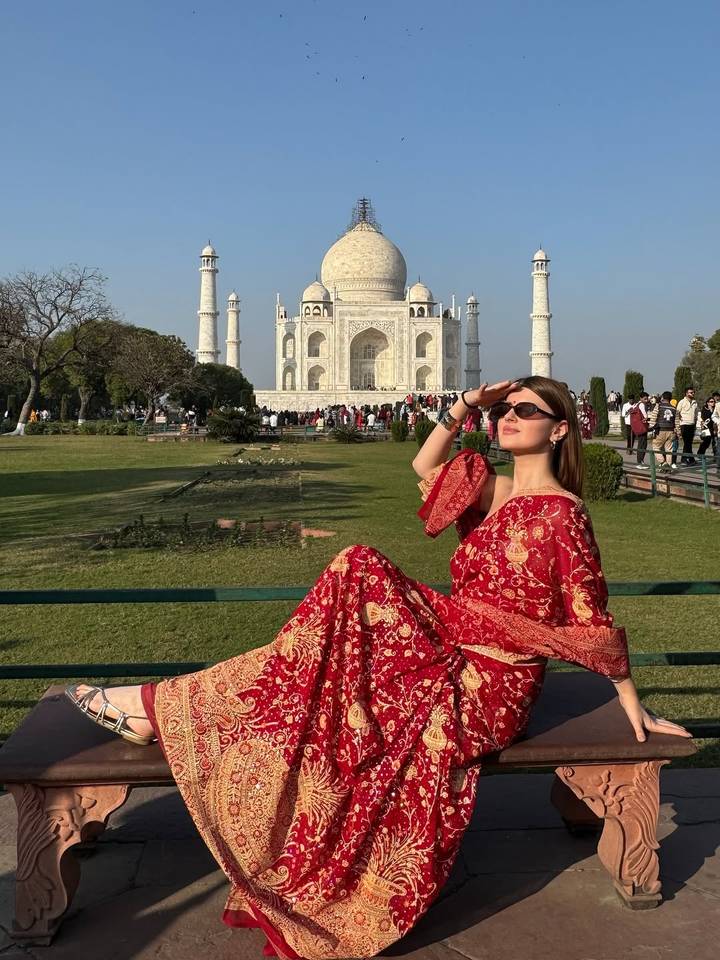 Femme posant sur un banc devant le Taj Mahal.