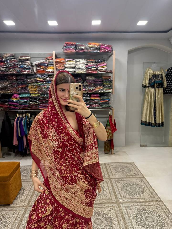 Femme prenant un selfie dans un magasin de vêtements avec des tenues traditionnelles.