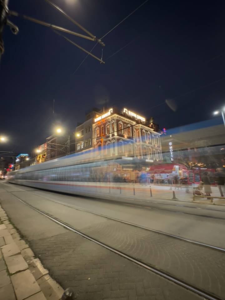 Tramway flou en mouvement la nuit dans une rue animée.