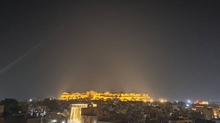 Un fort illuminé la nuit vu de loin.