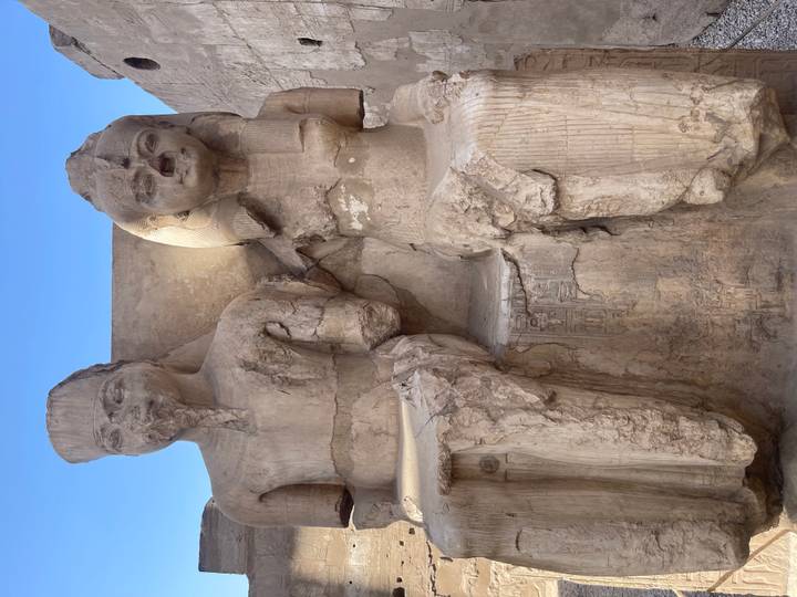 Dos estatuas antiguas sentadas una al lado de la otra, desgastadas y envejecidas.