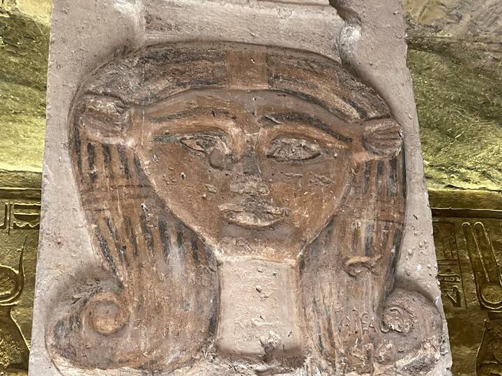Primer plano de un tallado del antiguo Egipto con un rostro y jeroglíficos.