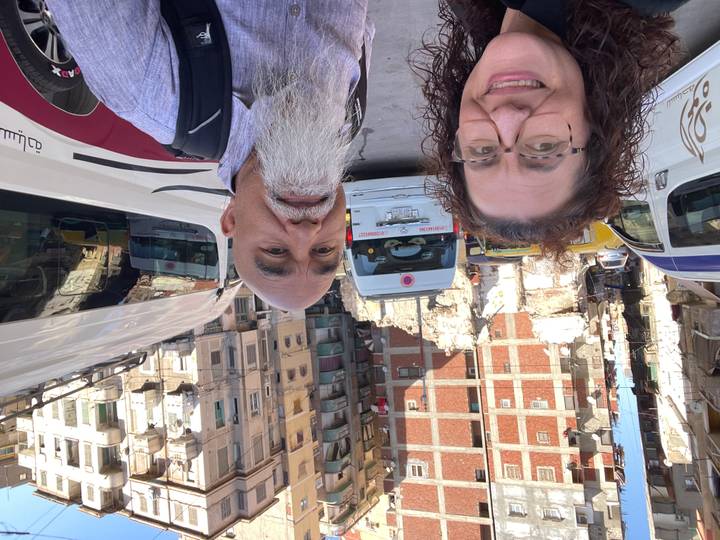 Vista de la calle con furgonetas y dos personas en primer plano.