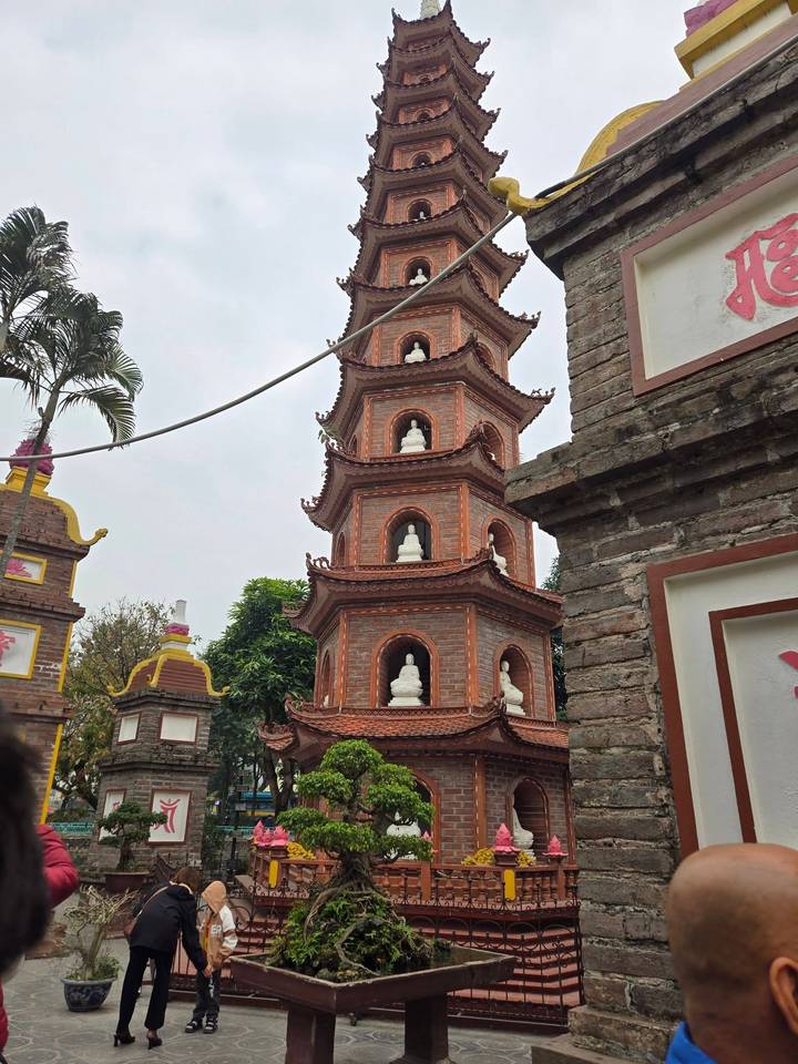 Torre de pagoda de ladrillo con pequeñas estatuas blancas.