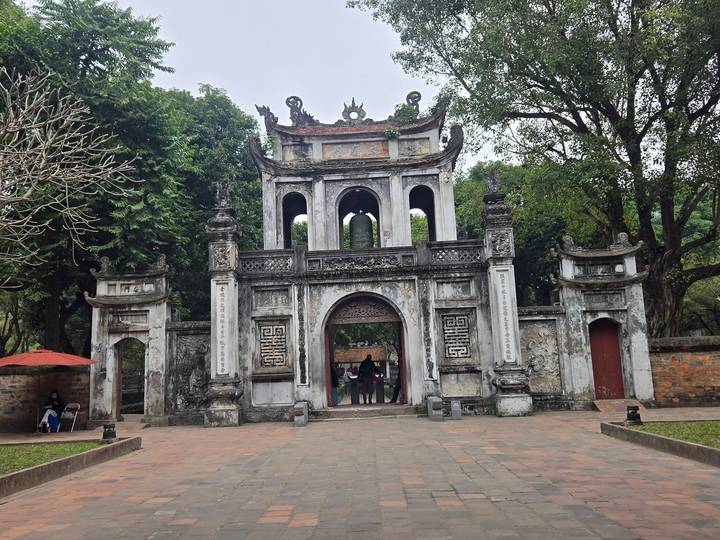 Entrada ornamentada de templo con puerta grande y árboles.