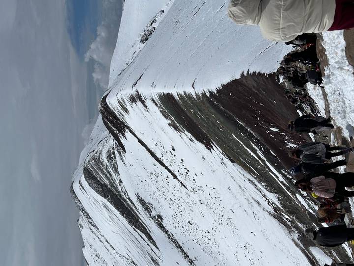 People climbing a snow-covered ridge on a mountain.