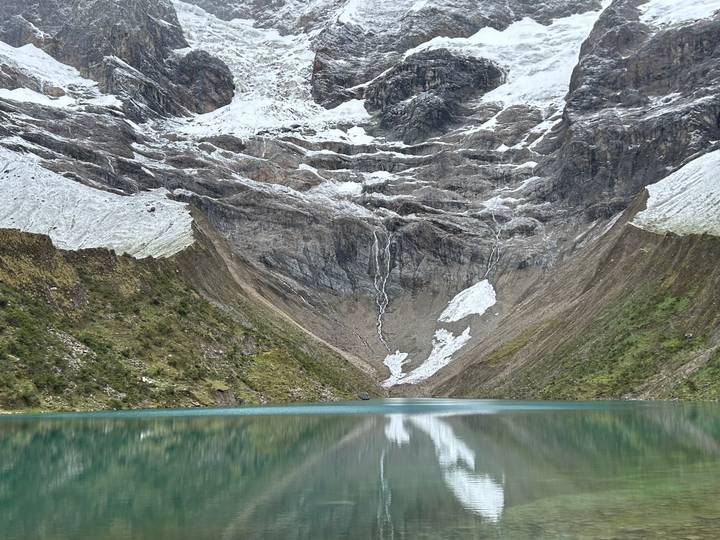 Mountain valley with glacial lake and snowcapped peaks.