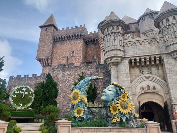 Estructura similar a un castillo con una estatua decorativa y el reloj de Ba Na Hills.