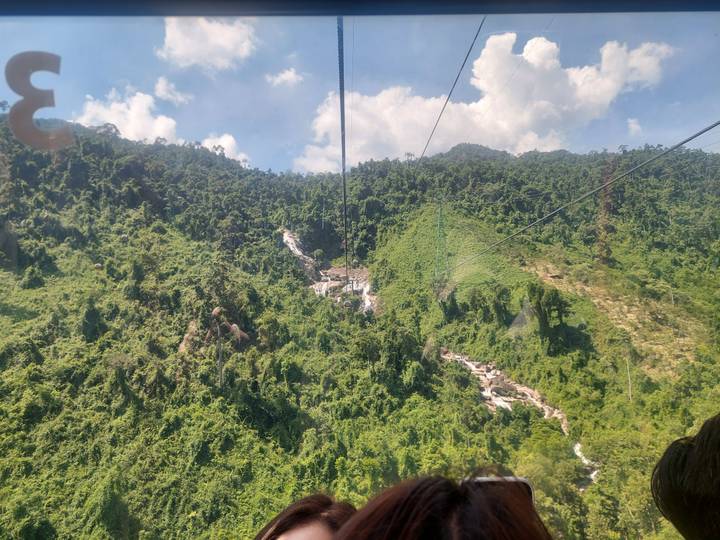 Vista panorámica desde un teleférico sobre bosques verdes y colinas.
