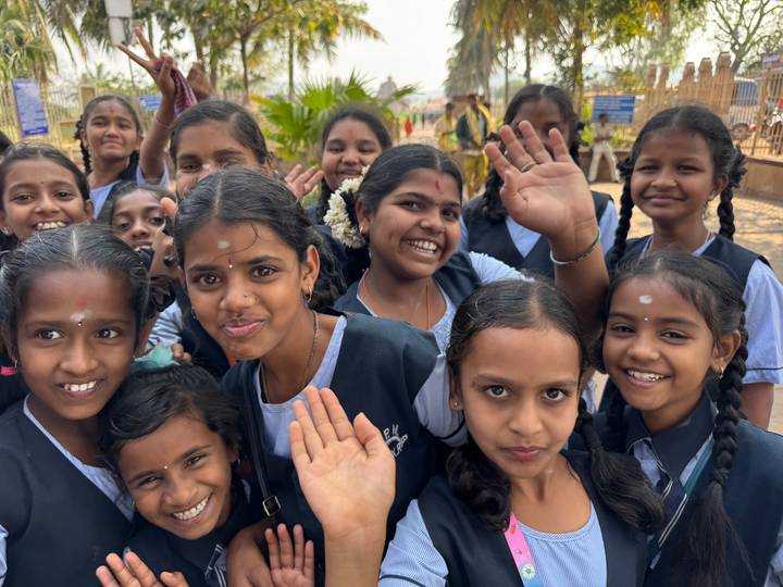 Un grupo de niños escolares sonriendo y saludando a la cámara.