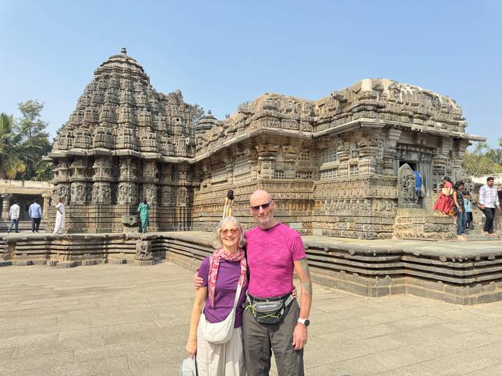 Una pareja posando frente a un templo antiguo intrincadamente tallado.