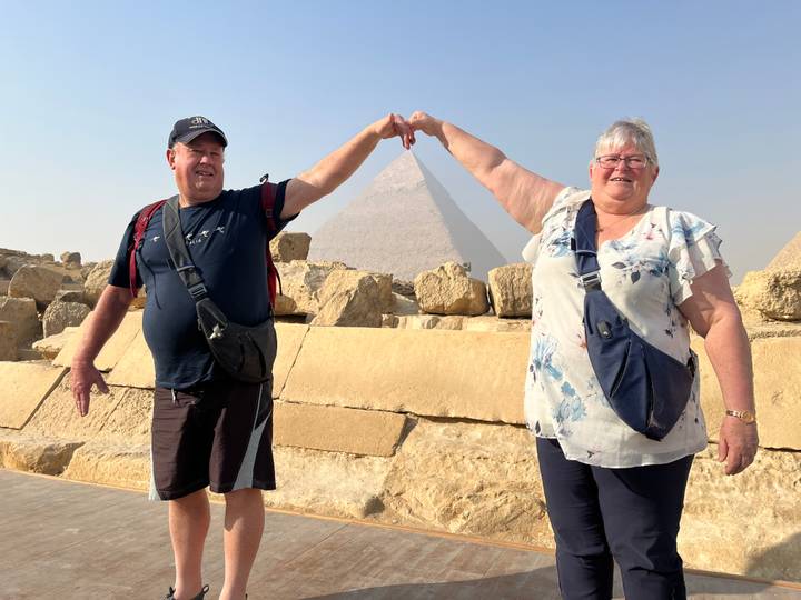 Deux personnes posant avec la pyramide de Gizeh en arrière-plan.