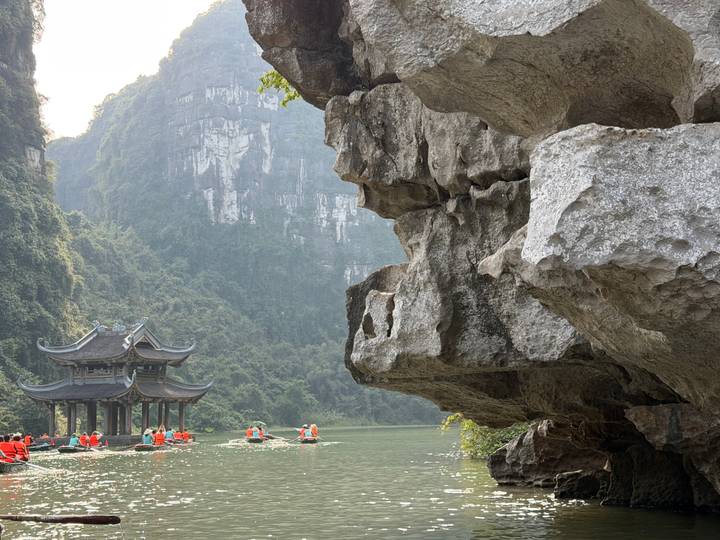Gente en botes en un río, acantilados de piedra caliza al fondo.