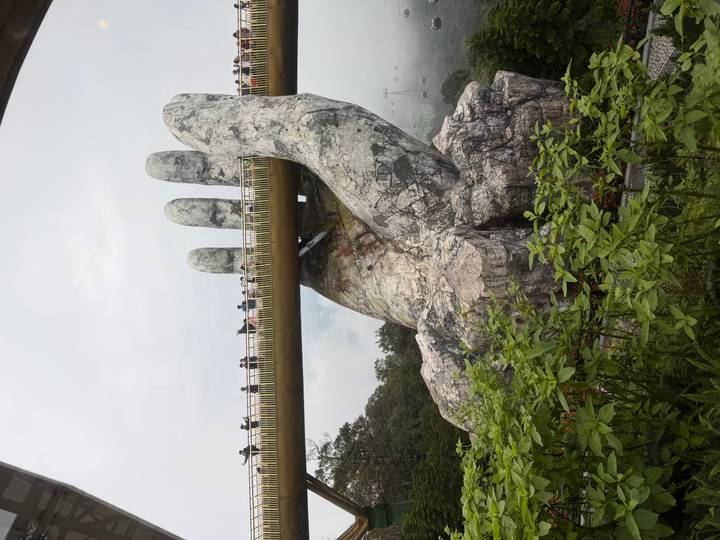 Manos gigantes sosteniendo un puente con gente caminando sobre él.