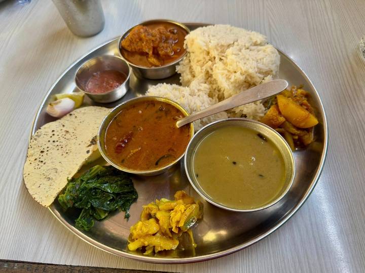 Una comida tradicional nepalí servida en una bandeja de metal.