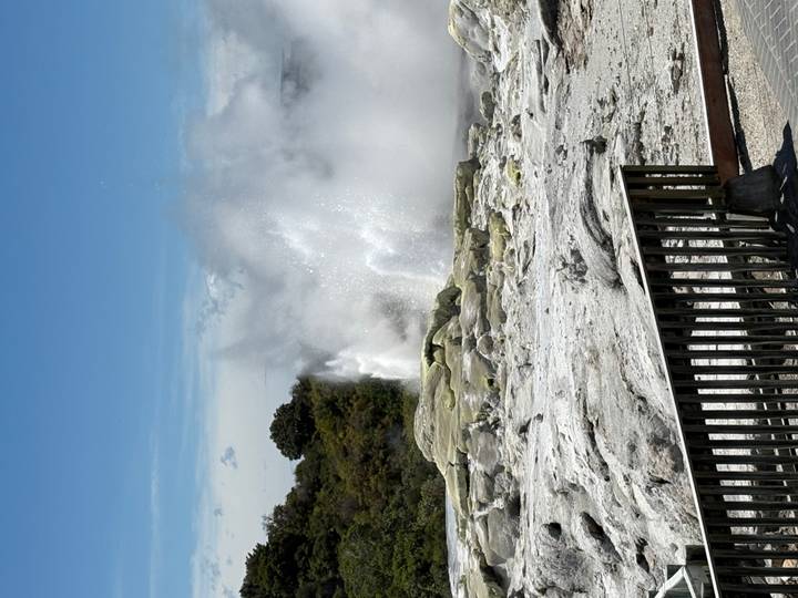 Un geyser en éruption avec un ciel dégagé en arrière-plan.