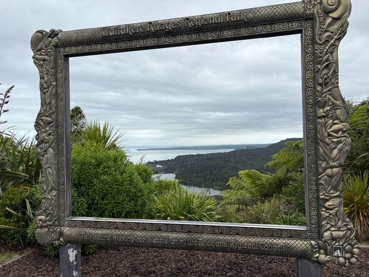 Vue panoramique à travers un cadre décoratif montrant un paysage.