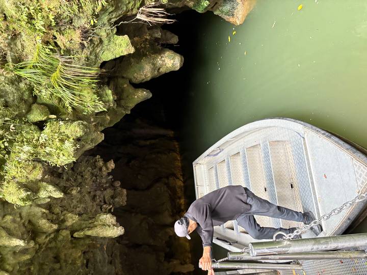 Une personne debout sur un bateau à l'entrée d'une grotte.