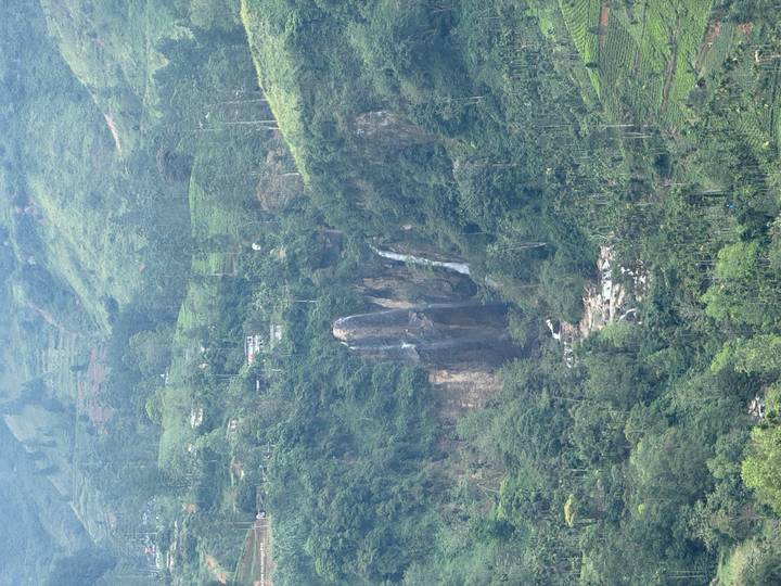 Cascada cayendo por la ladera verde y exuberante de una montaña.
