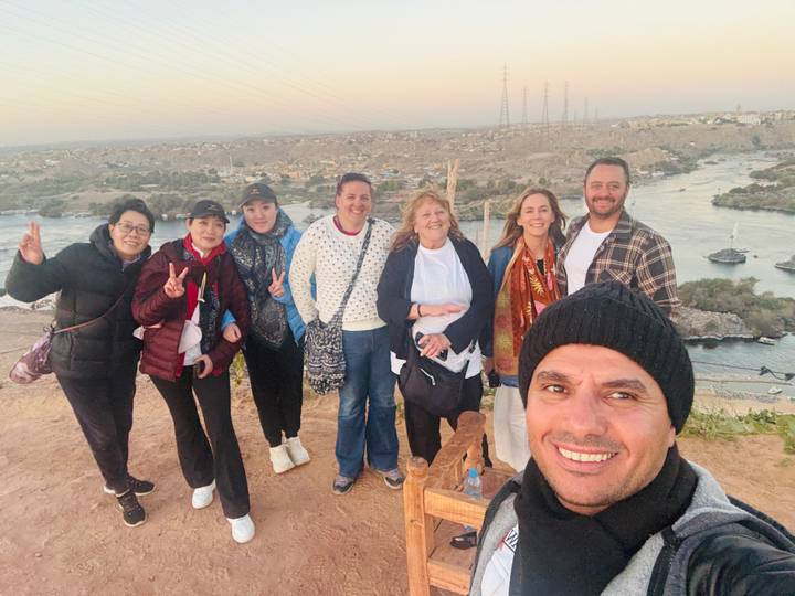 Group posing beside a river at sunset or sunrise.