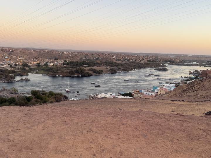 Riverside village at sunset with boats in the water.