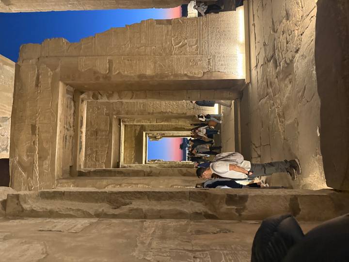 Ancient ruins with ornate carvings, people walking through.