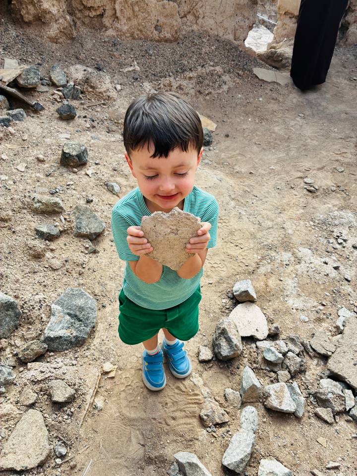Enfant tenant une pierre en forme de cœur avec un sourire.