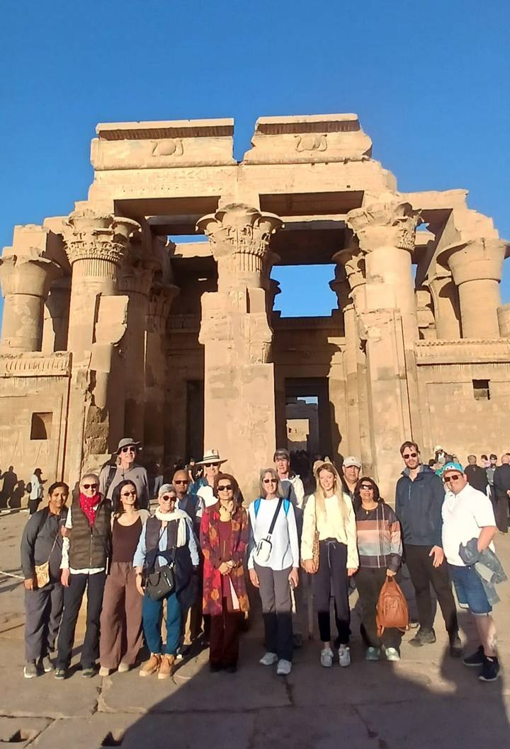 Grupo de turistas posando frente a un templo antiguo.