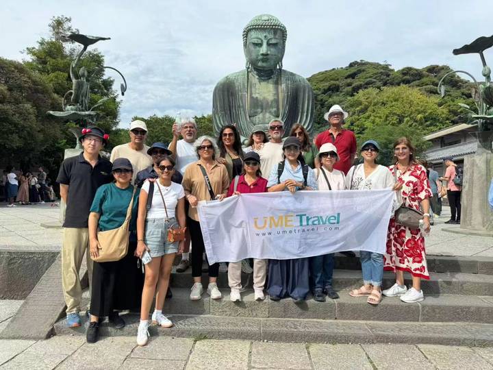Grupo de turistas con una gran estatua de Buda al fondo.