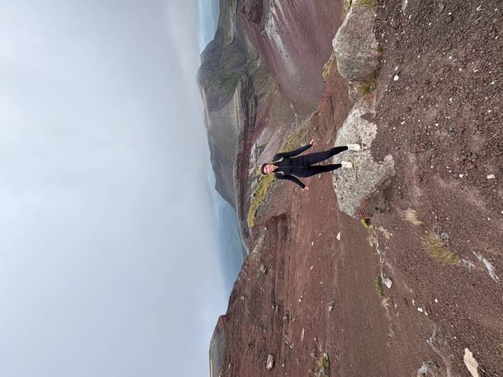 Individu posant sur un terrain volcanique rouge.