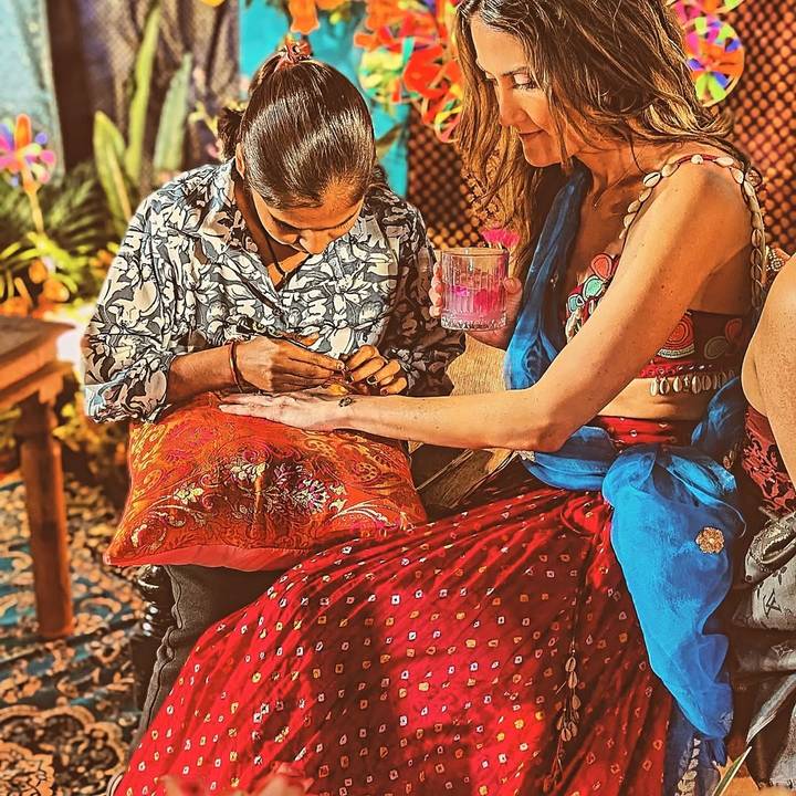 Une femme qui se fait faire un tatouage au henné tout en tenant une boisson.