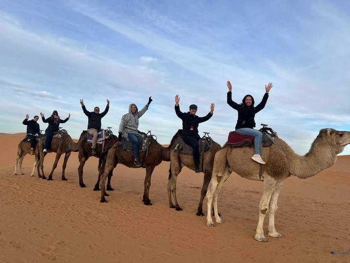 Groupe de personnes montant des chameaux dans un paysage désertique.