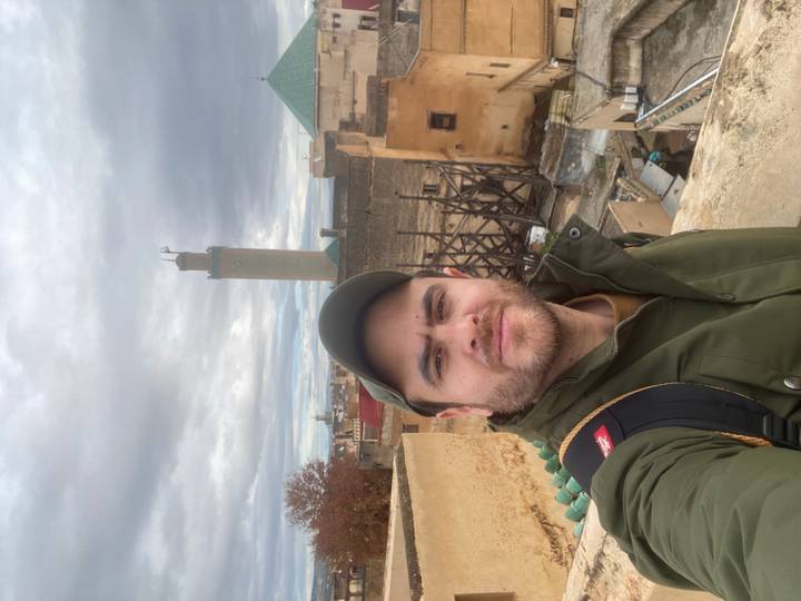 Personne prenant un selfie avec un paysage urbain et un minaret en arrière-plan.