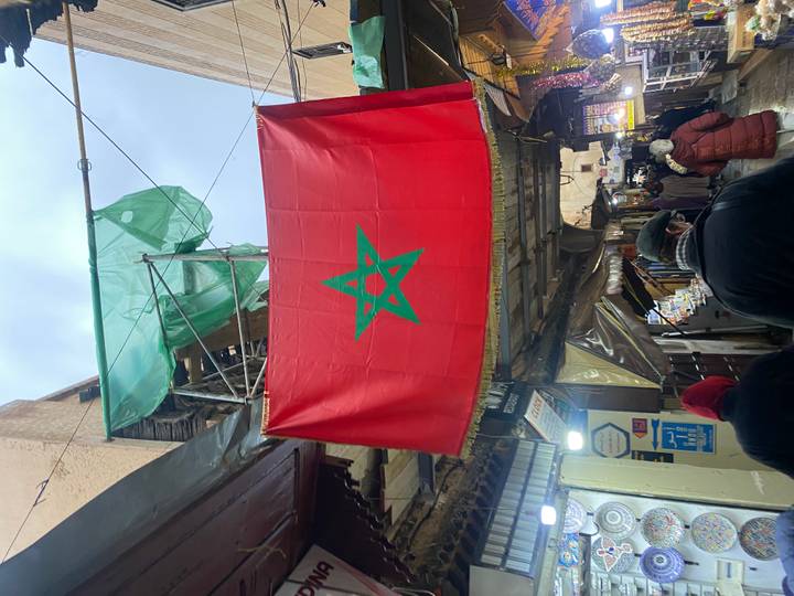 Drapeau marocain suspendu dans un marché animé.