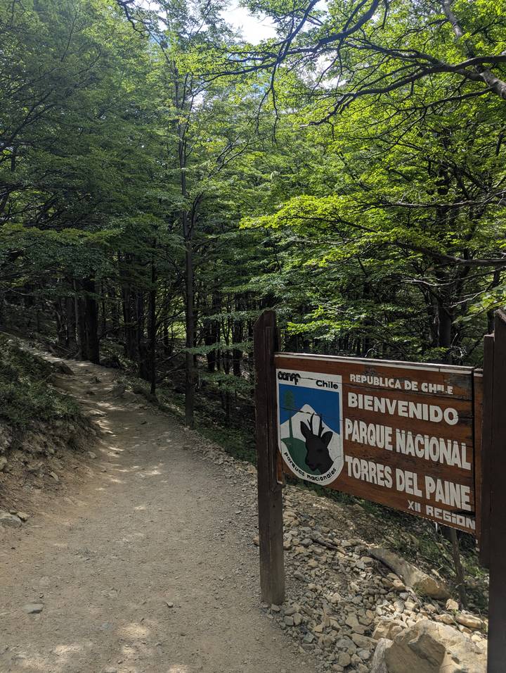 Letrero de entrada del Parque Nacional Torres del Paine junto a un sendero de tierra.