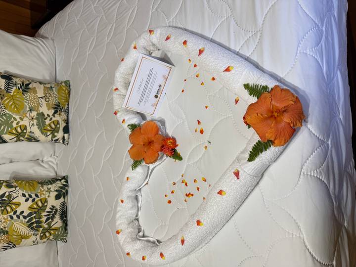 Arrangement décoratif de serviettes avec des fleurs sur un lit.