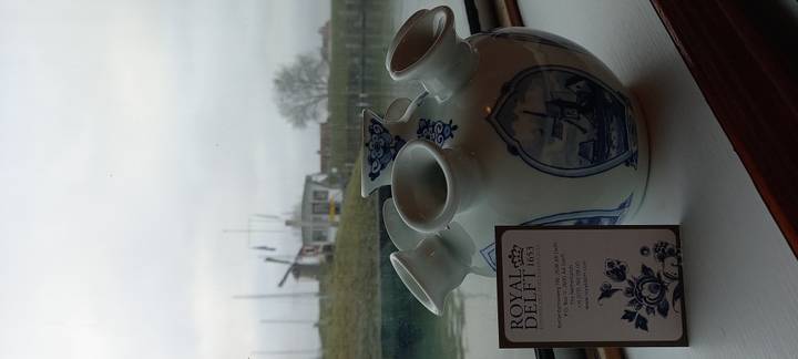 Vase en porcelaine avec motif de Delft sur un rebord de fenêtre avec vue sur l'eau.