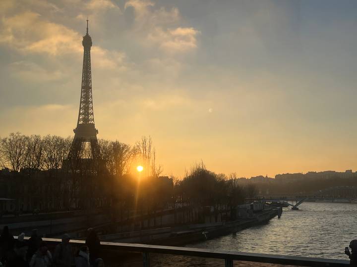 Torre Eiffel al atardecer con el río en primer plano.