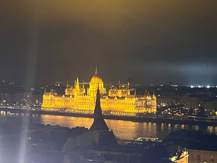 Edificio histórico iluminado por la noche reflejándose en un río.