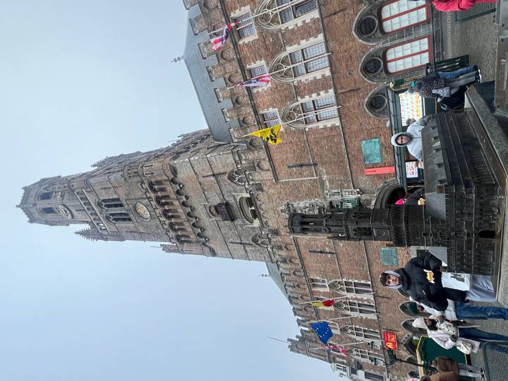 Edificio histórico alto con una maqueta pequeña en la base, cielo nublado.