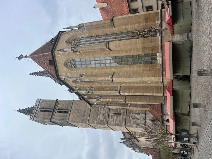 Catedral de piedra bajo un cielo nublado con puestos de vendedores cerrados.