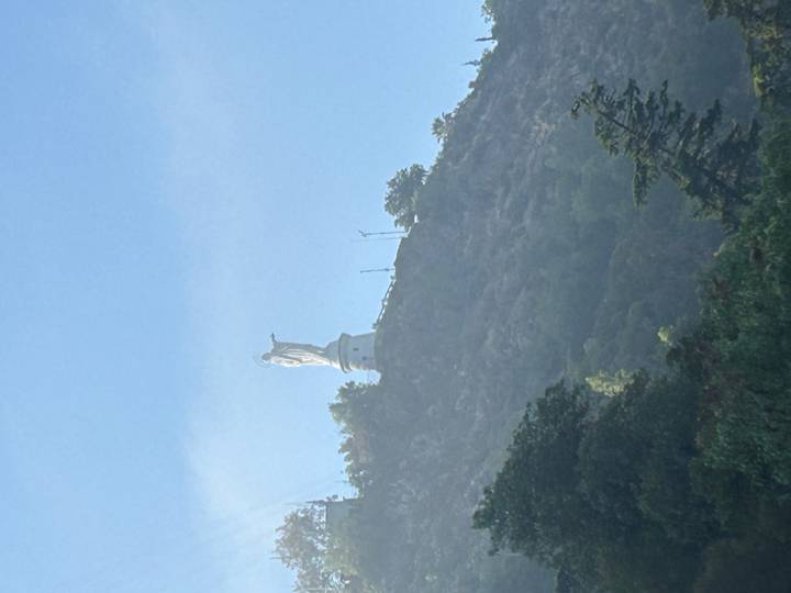 Estatua de la Virgen María en la cima de una colina rodeada de niebla.