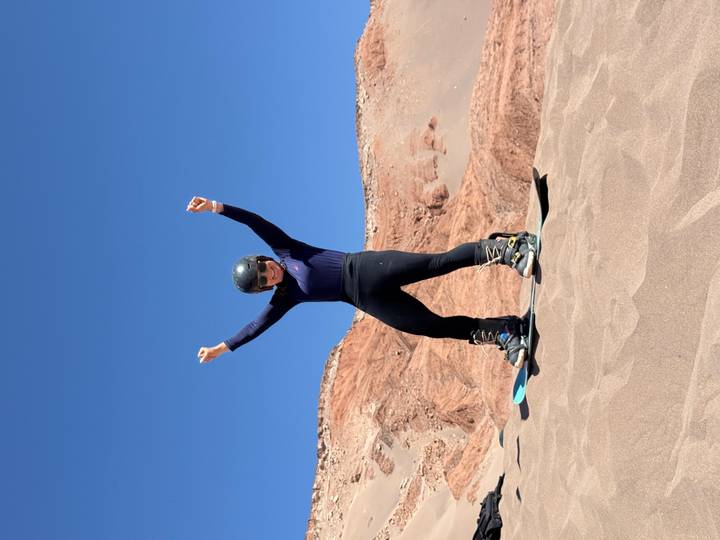 Mujer haciendo sandboard en un paisaje desértico.