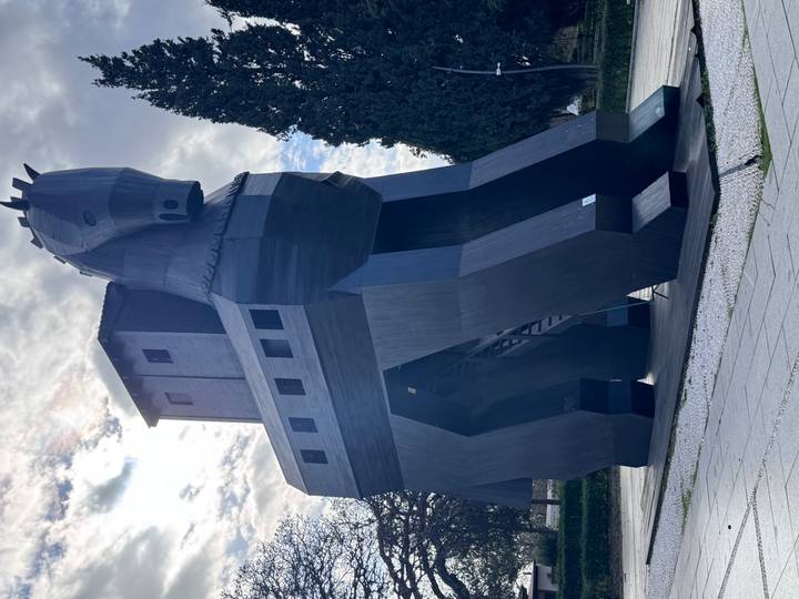 Estatua gigante de caballo de madera situada en un parque.