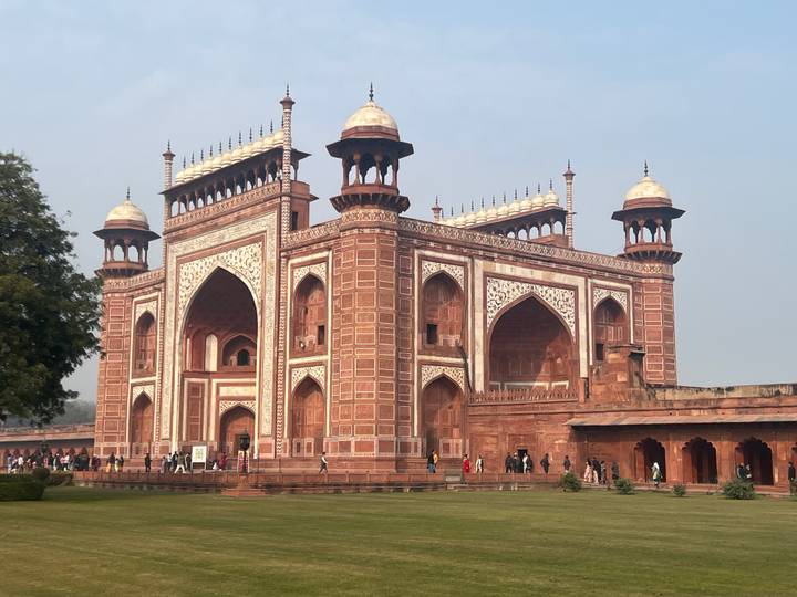Red sandstone gateway structure with tourists.