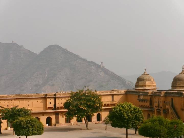 Una fortaleza histórica con montañas al fondo bajo un cielo brumoso.
