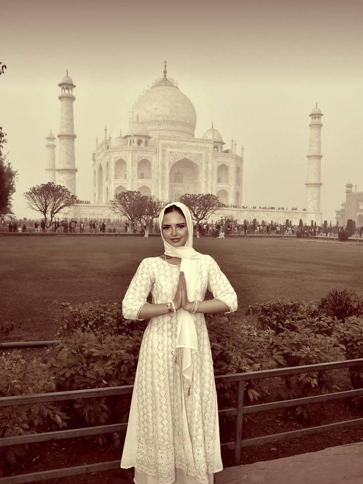 Una persona posando con gracia frente al Taj Mahal en tono sepia.