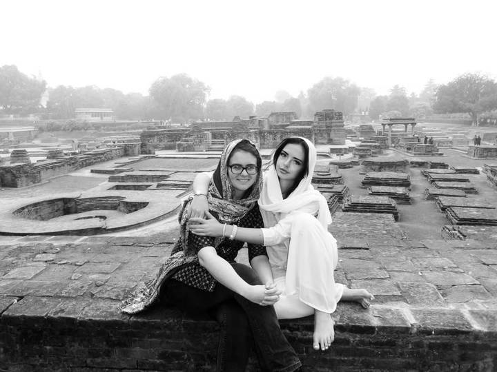 Dos personas sentadas entre ruinas antiguas.