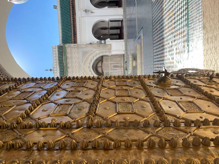 Porte en bois ornée s'ouvrant sur une cour au Maroc.