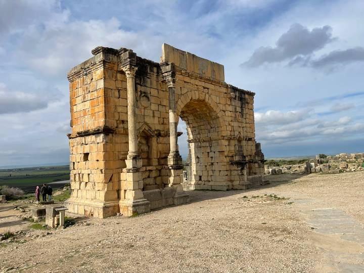 Arche historique à Volubilis avec un ciel nuageux.
